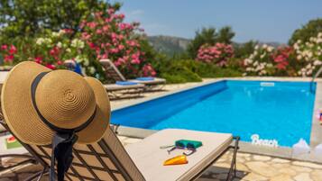 A poolside area with lounge chairs, a hat, sunglasses, and a beach sign.