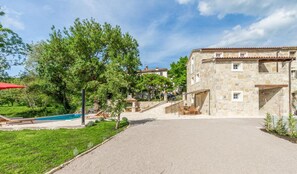 Un bâtiment en pierre doté d’une piscine et d’un espace extérieur aménagé pour s’asseoir.