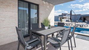 Eine Außenpatio mit Tisch und Stühlen, einem Pool und Blick auf andere Gebäude.