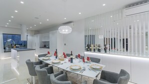 Een moderne eethoek met een lange tafel voor zes personen, omringd door grijze stoelen.