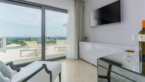 Een moderne woonkamer met een groot raam, een flatscreen televisie, een glazen tafel en een eethoek.