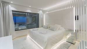 Een moderne slaapkamer met een groot bed, een glazen scheidingsraam en een nachtkastje.