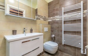 Uma casa de banho moderna com uma pia branca, sanita e um suporte para toalhas.