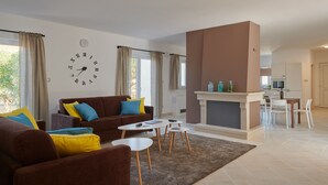 A modern living room with a sofa, coffee table, and fireplace. There is a dining area with a table and chairs. A kitchen is visible in the background. - Nella Hvar in Rudina Hvar (Stari Grad)