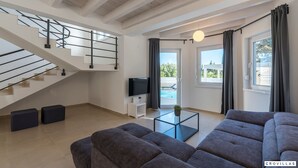 Een moderne woonkamer met een trap, een flatscreen televisie, een glazen salontafel en een grote bank.