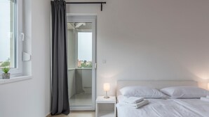 Een moderne hotelkamer met een bed, nachtkastje en een raam met gordijn.