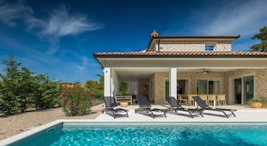 Une maison moderne dotée d’une piscine, d’un espace salon extérieur et d’un patio.