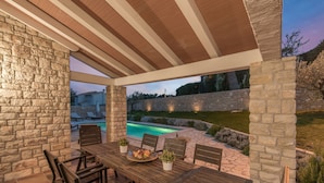 An outdoor patio with a pool, stone walls, and wooden furniture. - Kvarta in Barban With 3 Bedrooms and 3 Bathrooms (Barban)