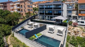 Un edificio moderno con piscina en la azotea, zona de estar al aire libre y parque infantil.