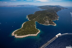 Vista aérea de uma área costeira com várias ilhas, águas azuis cristalinas e um barco em primeiro plano.