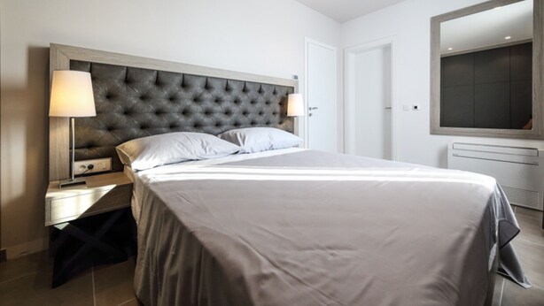 Ein modernes Hotelzimmer mit einem großen Bett, zwei Nachttischen mit Lampen, einem Flachbildfernseher und einer integrierten Heizung.