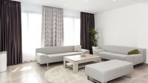 Ein modernes Wohnzimmer mit zwei Sofas, einem Couchtisch und einem Blumentopf.