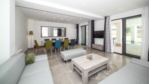 Ein modernes Wohnzimmer mit einer Couch, einem Couchtisch und einem Essbereich mit Stühlen und einem Tisch.
