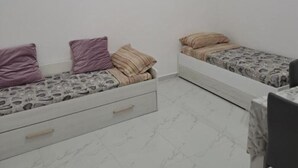 A small, sparsely furnished room with two beds, a desk, and a chair. - Giorgia's House (Campofelice di Roccella)