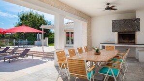 An outdoor patio with a dining table and chairs, a ceiling fan, and a fireplace. - Design Sole in Svetvin Enat (Svetvincenat)