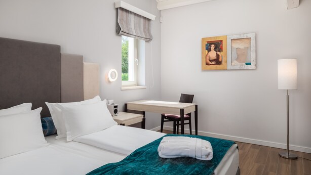 A hotel room with a bed, a desk, a chair, a lamp, and artwork on the wall. - Design Sole in Svetvin Enat (Svetvincenat)