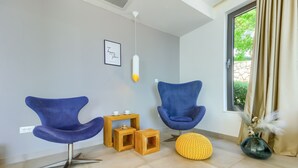 A modern living room with two blue chairs, a wooden side table, a yellow pouf, and a vase with dried plants. - Bellevue in Bast Ba ka Voda (Baska Voda)