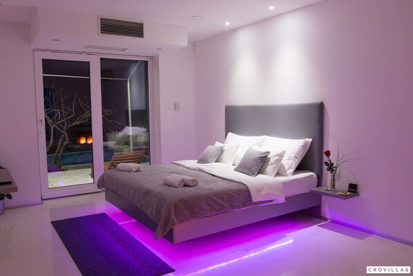 Une chambre moderne avec un lit, une table de chevet et une vue sur une piscine à l’extérieur.