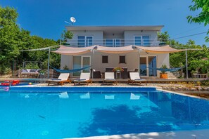 Une maison moderne dotée d’une piscine, de chaises longues et d’un hamac.