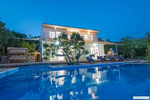 Une maison moderne à deux étages avec une piscine à l’avant.