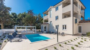 A multi-story building with a swimming pool, outdoor seating, and a pergola. - Complex Kamenjak in Premantura (Medulin)
