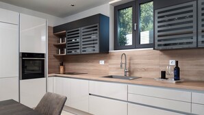 A modern kitchen with a built-in oven, a stainless steel sink, and a window above the countertop. - Four Seasons Vrsi in Vrsi (Vrsi)