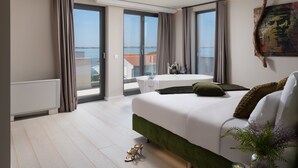 A modern bedroom with a large bed, a small table, and a view of the sea through the windows. - Four Seasons Vrsi in Vrsi (Vrsi)