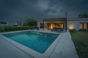 Ein moderner Poolbereich im Freien mit überdachter Sitzgelegenheit und Bar.