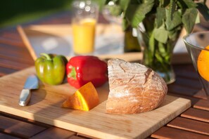 A wooden cutting board with a loaf of bread, a knife, a red bell pepper, a green bell pepper, and a glass of orange juice. - Seksta in Barban With 4 Bedrooms and 4 Bathrooms (Barban)