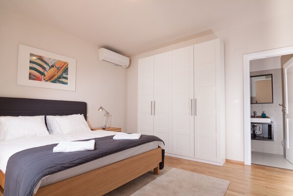 A bedroom with a bed, a wardrobe, and a bathroom visible through an open door. - Seksta in Barban With 4 Bedrooms and 4 Bathrooms (Barban)