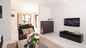 Una sala de estar moderna con sofá, mesa de centro, televisor y mueble de entretenimiento.