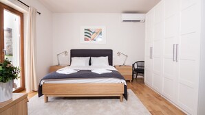 Un dormitorio con cama de madera, una mesita de noche, una lámpara de escritorio, una silla y un armario.