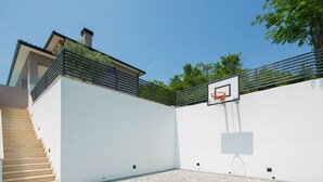 A modern outdoor basketball court with a white wall, a wooden staircase, and a metal railing. - Arsia in Labin With 4 Bedrooms and 4 Bathrooms (Rasa)