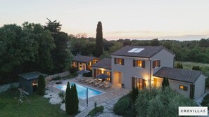 Una vila moderna amb piscina, zona de seients a l'exterior i jardí ben cuidat.