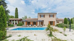 Eine moderne Villa mit Swimmingpool, Sitzgelegenheiten im Freien und einem gepflegten Garten.