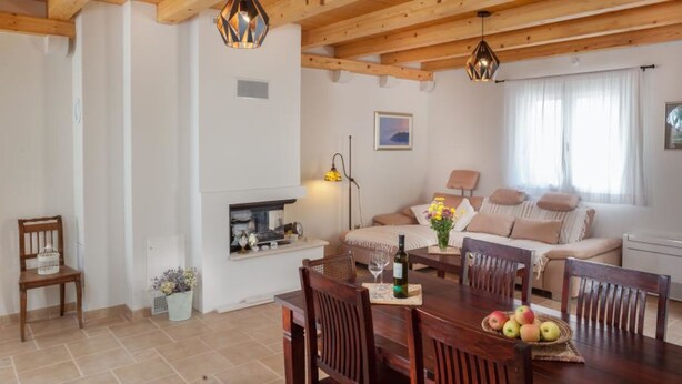 A cozy living room with a wooden dining table, chairs, a sofa, and a fireplace. - Makar in Makarska With 2 Bedrooms and 1 Bathrooms (Makarska)