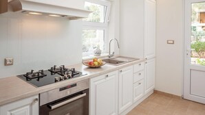 A modern kitchen with white cabinetry, a gas stove, an oven, and a sink with a window above it. - Makar in Makarska With 2 Bedrooms and 1 Bathrooms (Makarska)