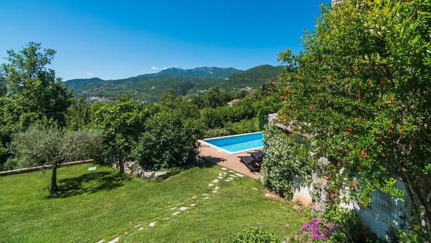 A pool surrounded by lush greenery and mountains in the background. - Marina Opatija in Opatija (Opatija)