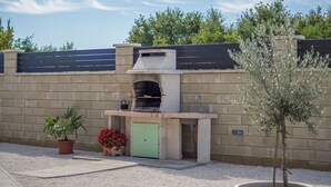 An outdoor kitchen with a stone wall, a green door, and potted plants.