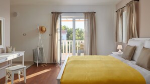 A bedroom with a bed, a desk, and a chair. There is a balcony with curtains and a hat hanging on the wall. - Susanna Hvar in Rudina Hvar (Stari Grad)
