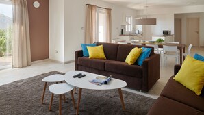 A modern living room with a brown sofa, two white coffee tables, and yellow cushions. A dining area with a white table and chairs is visible in the background. - Susanna Hvar in Rudina Hvar (Stari Grad)