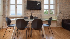 Een eethoek met een stenen muur, een flatscreen televisie boven een tafel en drie stoelen.