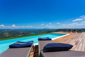 A poolside area with lounge chairs and a view of a mountain landscape. - Vista in Zamask With 3 Bedrooms and 3 Bathrooms (Pazin)