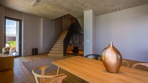 A modern interior with a wooden dining table, a vase, and a staircase leading to a loft area. - Vista in Zamask With 3 Bedrooms and 3 Bathrooms (Pazin)