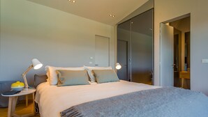 A modern bedroom with a large bed, two bedside lamps, a bedside table with a lamp, and a mirror. - Vista in Zamask With 3 Bedrooms and 3 Bathrooms (Pazin)
