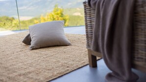 A room with a view of mountains, a wicker chair with a blanket, and a textured rug. - Vista in Zamask With 3 Bedrooms and 3 Bathrooms (Pazin)