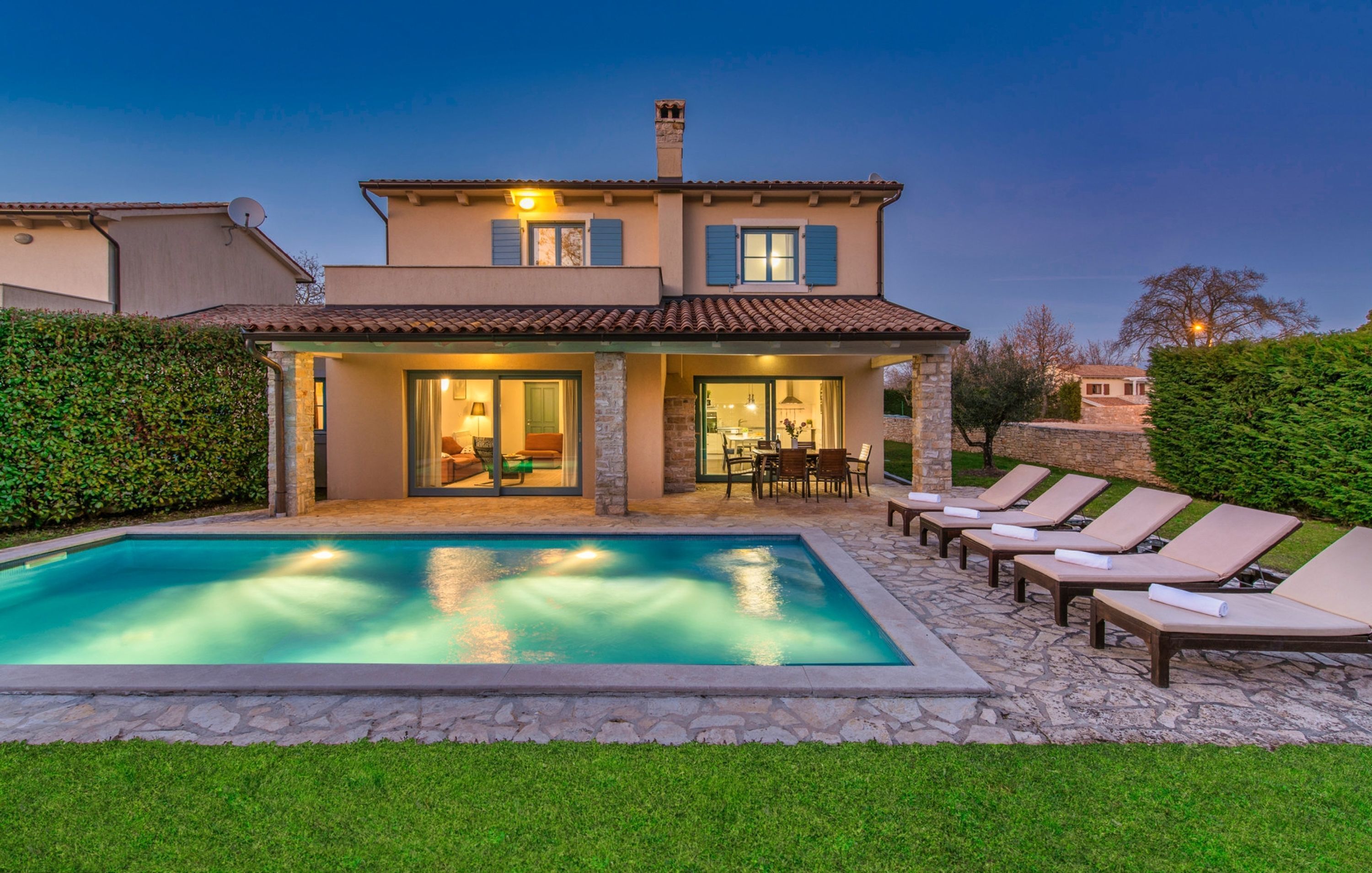 A two-story house with a swimming pool, outdoor seating, and a well-maintained garden.