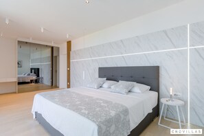 A modern bedroom with a large bed, marble-patterned walls, and a small bedside table with a lamp. - Pax in Sutivan With 3 Bedrooms and 3 Bathrooms (Sutivan)