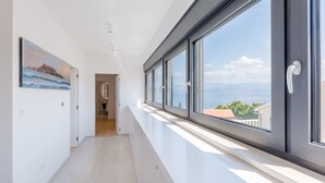 Un pasillo moderno con ventanas amplias, un cuadro en la pared y vista al mar.