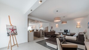 A modern living room with a sofa set, a dining area, and a kitchen in the background. - Dalmacija Viii in Suko an (Sukosan)